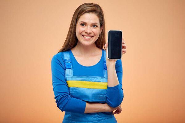 Woman in overalls holding smartphone in front of him. Isolated female  worker portrait.