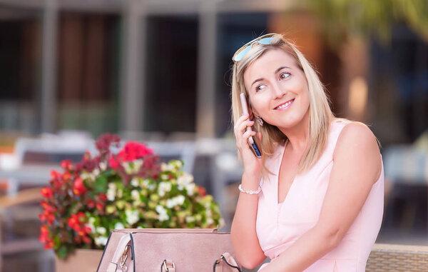 Cute woman talking with someone on mobile phone in a restaurant terrace