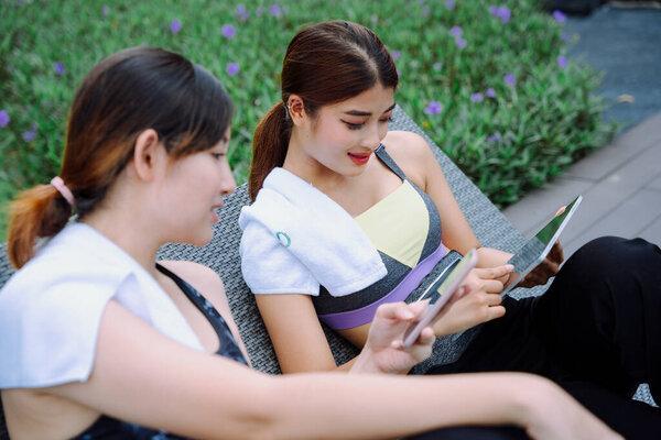 Beautiful healthy women relax on a chair, online shopping with smartphone and laptop.