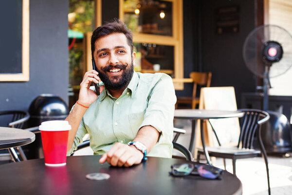 Bearded indian man using  his smartphone 