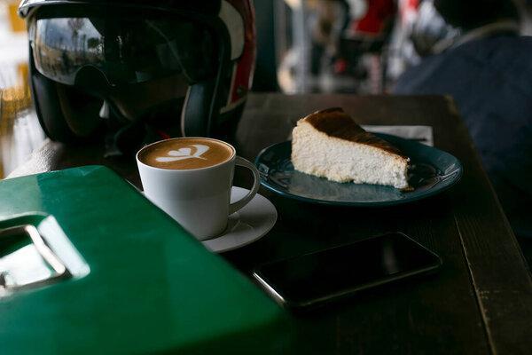 A slice of cake and coffee on a wooden table. Helmet