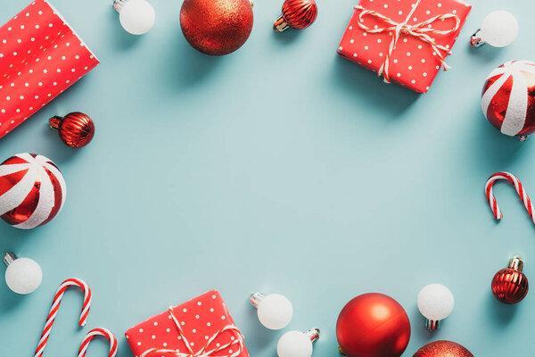 Vintage Christmas frame with balls decoration, gift boxes, candy canes on blue background. Retro style Christmas card template. Flat lay, top view.