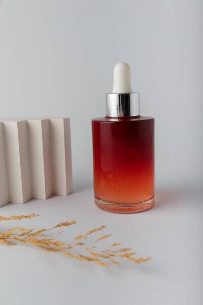 Serum bottle on white with some decor. Face skin care cosmetics mock up template, no label, no brand. Antioxidant ampoule acid