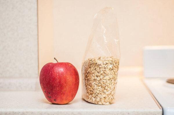 Dry oatmeal is on the kitchen table in a packing bag next to a l