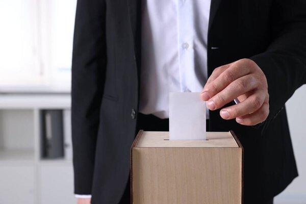 男子把他的选票放在室内投票箱，特写