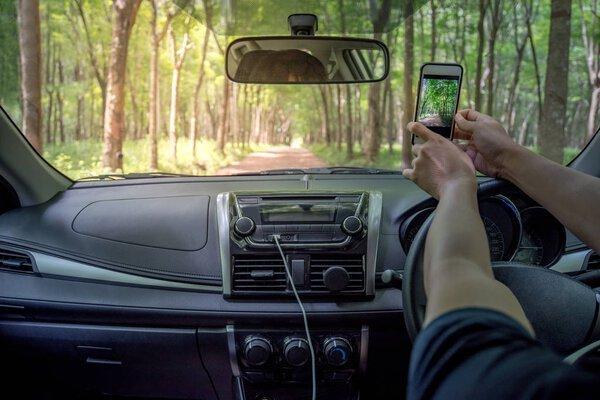 Driver's hands taking photo from smartphone inside of a car