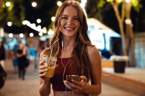 Optimistic happy woman walking by street using mobile phone.
