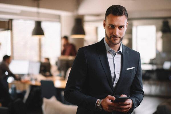 Businessman in suit using modern smartphone in the office.