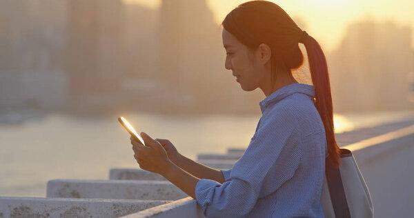 Woman use of cellphone under sunset in Hong Kong