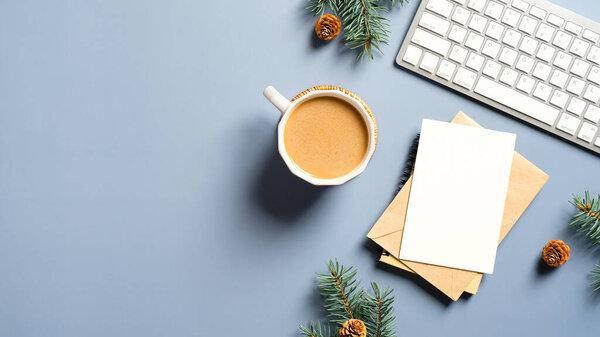 Home office table with Christmas decorations, coffee cup, keyboard, paper notebook. Flat lay, top view. Christmas workspace. Hygge, nordic, minimal style.