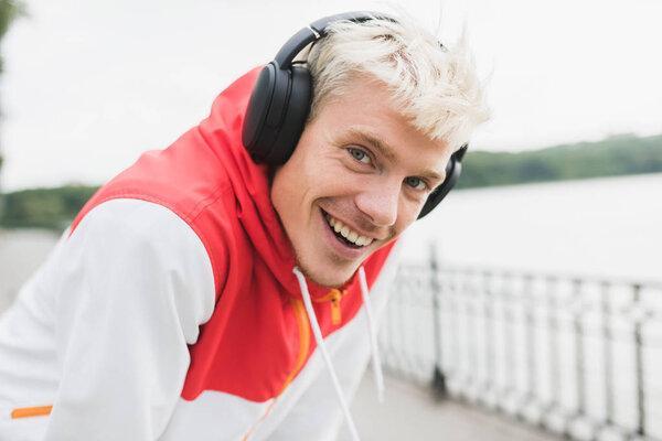 Positive portrait of happy male dressed in red sportswear restin