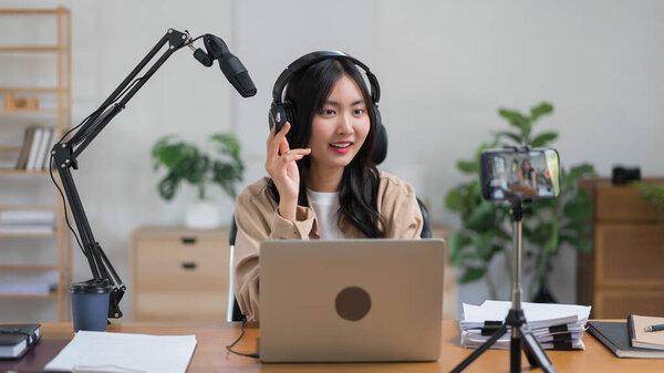 Female podcaster use microphone to talking with audience and recording video podcast on smartphone.