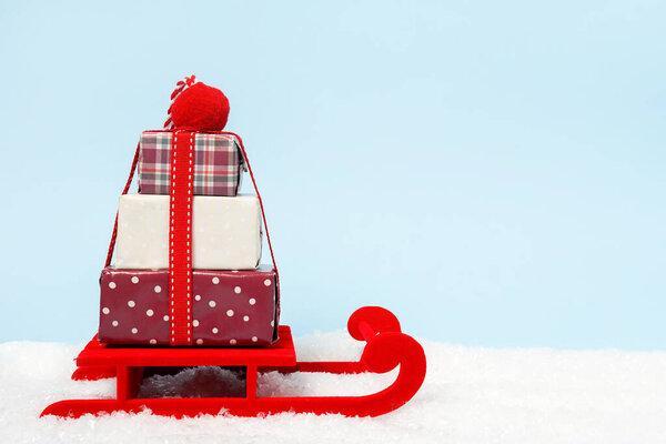 Christmas blue background with gift boxes on red sled. copy space