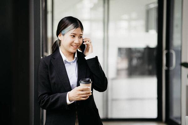 Asian woman talking on the phone, she is a salesperson in a startup company, she is calling customers to sell products and promotions. Concept of selling products through telephone channels.