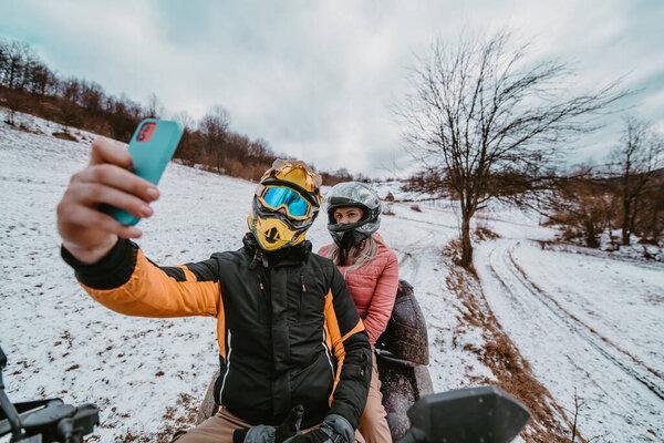  一对夫妇在雪地的风景中享受着冒险的四足旅行，在寒冷的仙境中，他们的智能手机上带着一个自拍，捕捉着那一刻的兴奋.