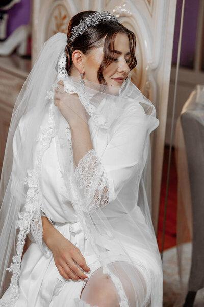 一个穿着婚纱的女人正坐在镜子前.她戴着面纱和项链