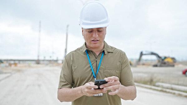 年轻的高加索人建筑师在建筑工地用智能手机