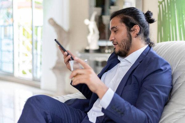 selective focus of businessman using smart phone and holding glass. Home Office