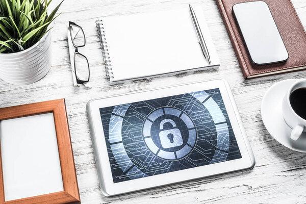 Business workplace with office stuff and tablet with padlock icons on screen
