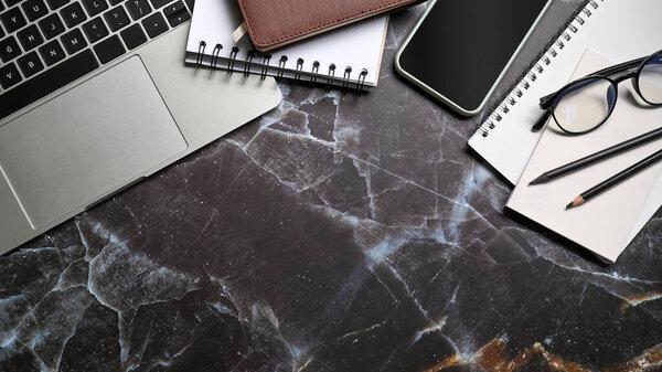Computer laptop, smart phone and notebooks on marble table. Workspace.