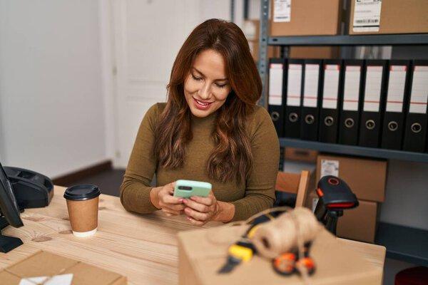 Young latin woman business worker using smartphone at office