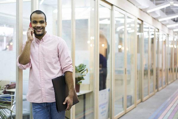 Portrait of cheerful young male employee of architect company happy to hear best friend on phone conversation
