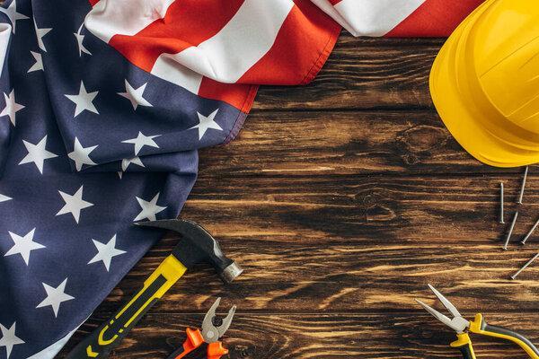 木质表面上安全帽附近的美国国旗和工具的俯视图，劳动节概念