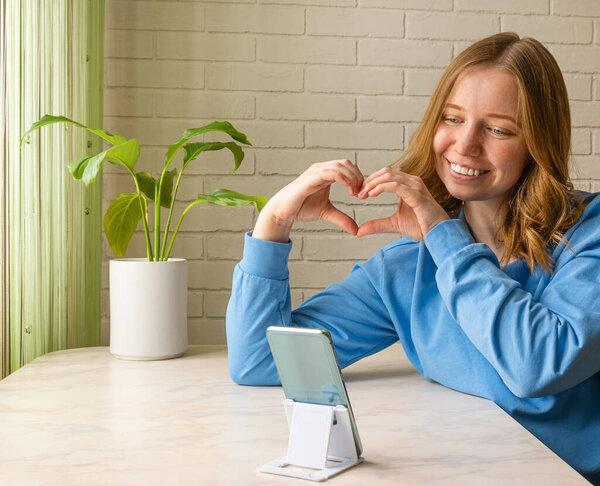 Online dating. young girl shows heart with her hands