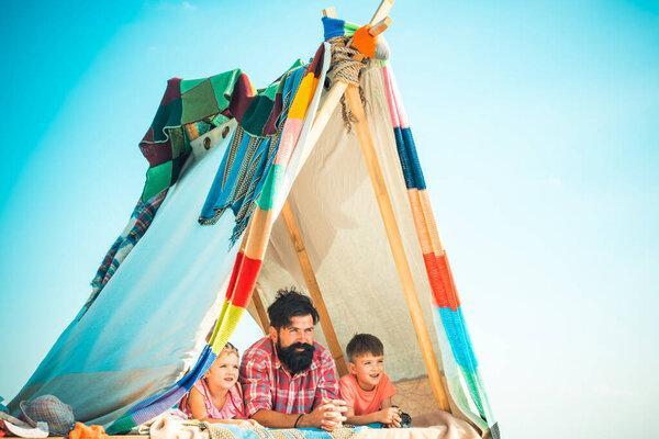 Dad with kids playing together in tent. Summer outdoor. Family playing together. Happy father with chidren, camping. Fathers day. Vacation concept.