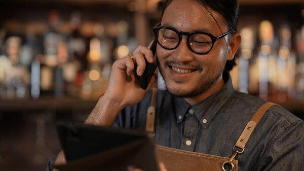 Night club concept of 4k Resolution. The bartender is taking orders from customers with the phone in the restaurant. A group of specialized clubs that sell alcoholic beverages.