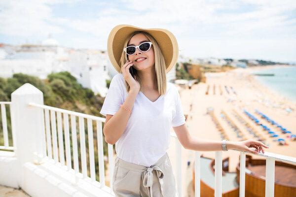 Beautiful woman leaning on the terrace railing, relaxing and having phone call