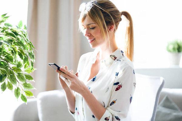 Charming beautiful young designer woman texting with her mobile phone at the office.