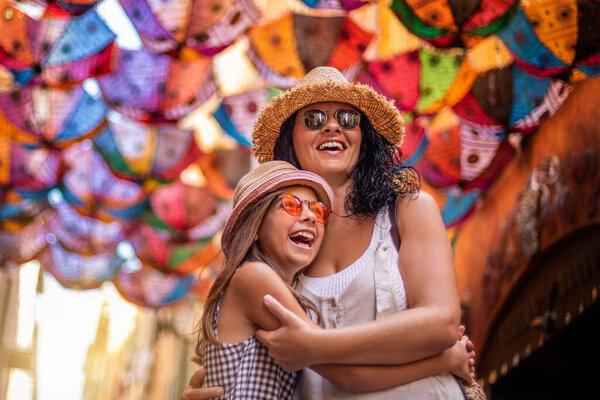 A smiling woman and her daughter walking at a street with ornament umbrellas. Vacation concept at Nice, France.