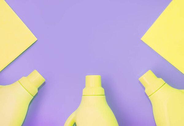 Yellow plastic bottles with chemicals for cleaning, rags for cleaning. Purple background. Cleaning concept