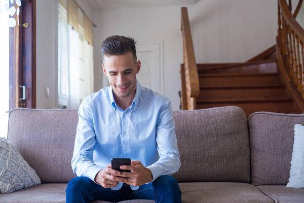 Excited smiling man looking at phone screen, using mobile app, typing message in social network, reading news, email, male student chatting with friends, playing game, watching funny video 