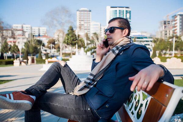 Handsome man with phone at the park.Man talking by phone,man use phone,stylish man in sunglasses using smartphone
