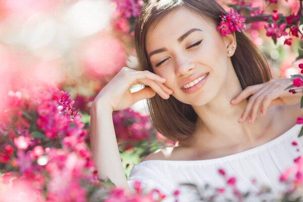 年轻女子特写的美丽肖像。花丛中的迷人女性。户外美丽的女士。