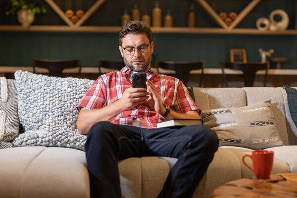 Freelance business man using mobile phone checking social media or message chat at home. Online working from home. Man rest after hard work day in living room. Guy using cell phone on sofa at home