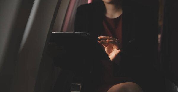 金发女郎的游客检查收到的通知, 智能手机坐在飞机的座位上与上网本。年轻的女实业家在飞机飞行期间与笔记本电脑上的电话共享媒体