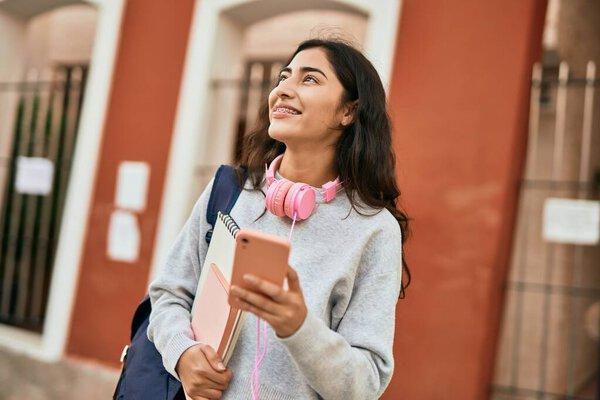 Young middle east student girl smiling happy using smartphone at the city.