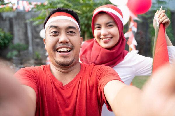young couple take selfies with cameras while wearing red and white attributes