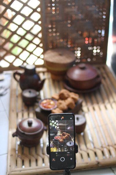 亚洲人在木制桌子上用手机，配黑咖啡和茶.