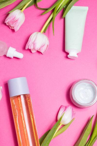 Beauty background with natural cosmetic, green leaves and flowers. Flat lay image on blue. High quality photo