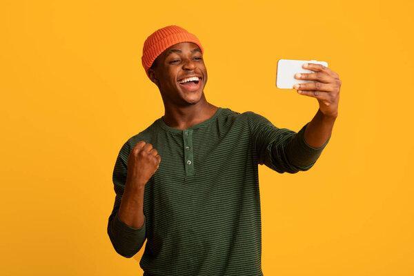 Online Win. Joyful Black Guy Looking At Smartphone Screen And Celebrating Success