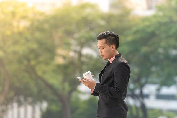 Young Malay Business Man on his Smartphone with a cup of coffee.