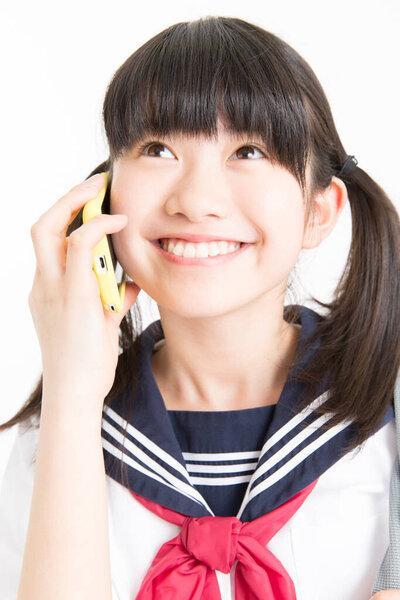 portrait of young Asian girl in school uniform talking over a mobile phone