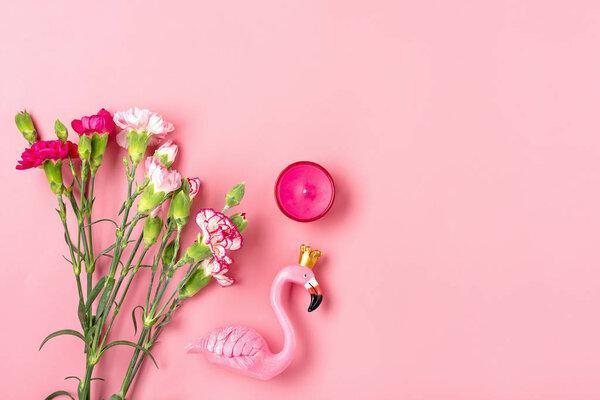 女性物品 - 火烈鸟、康乃馨花、粉色背景上的蜡烛 平铺 俯视图。三八节、情人节快乐、母亲节概念的模型展示假样。
