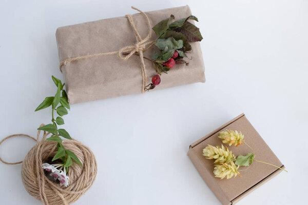 Eco friendly composition with gift box in craft reusable paper and  flower decor on white background. Holiday zero waste  concept.