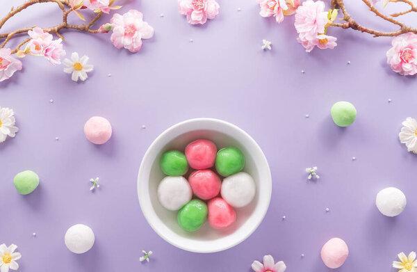 Tang Yuan(sweet dumplings balls), a traditional cuisine for Mid-autumn, Dongzhi (winter solstice ) and Chinese new year with plum flower on pastel background.