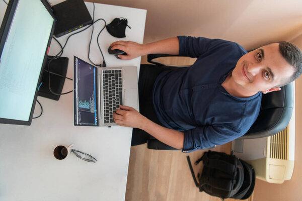 Top view of programmer diligently testing smartphone applications while sitting in their office
